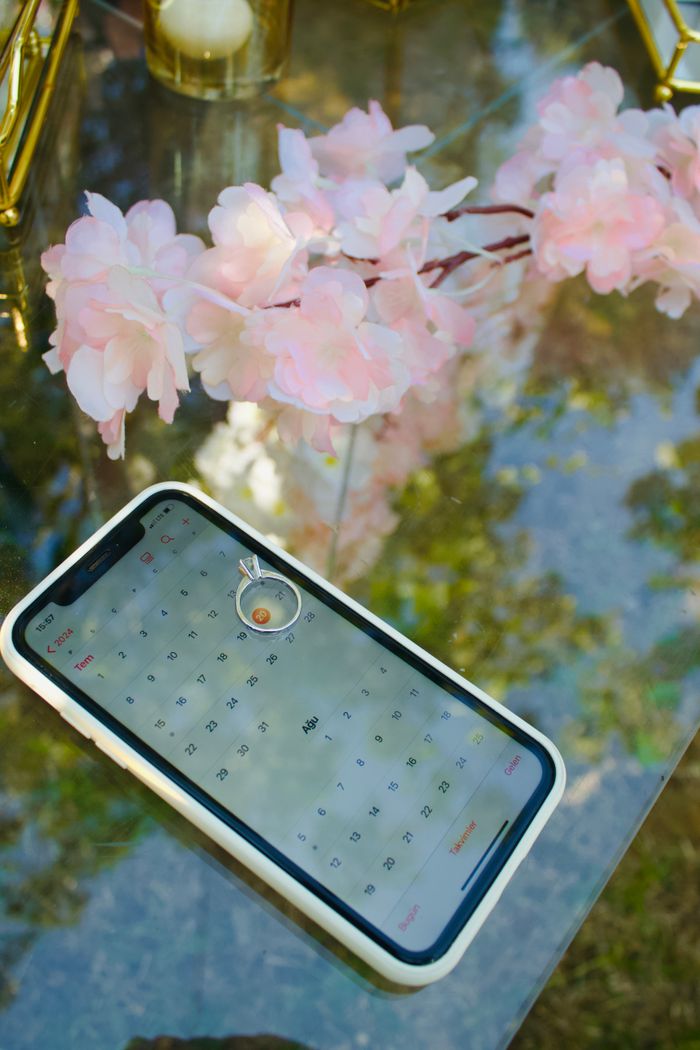 services-03 Engagement ring on smartphone calendar with pink flowers. Perfect for proposals and wedding planning visuals.