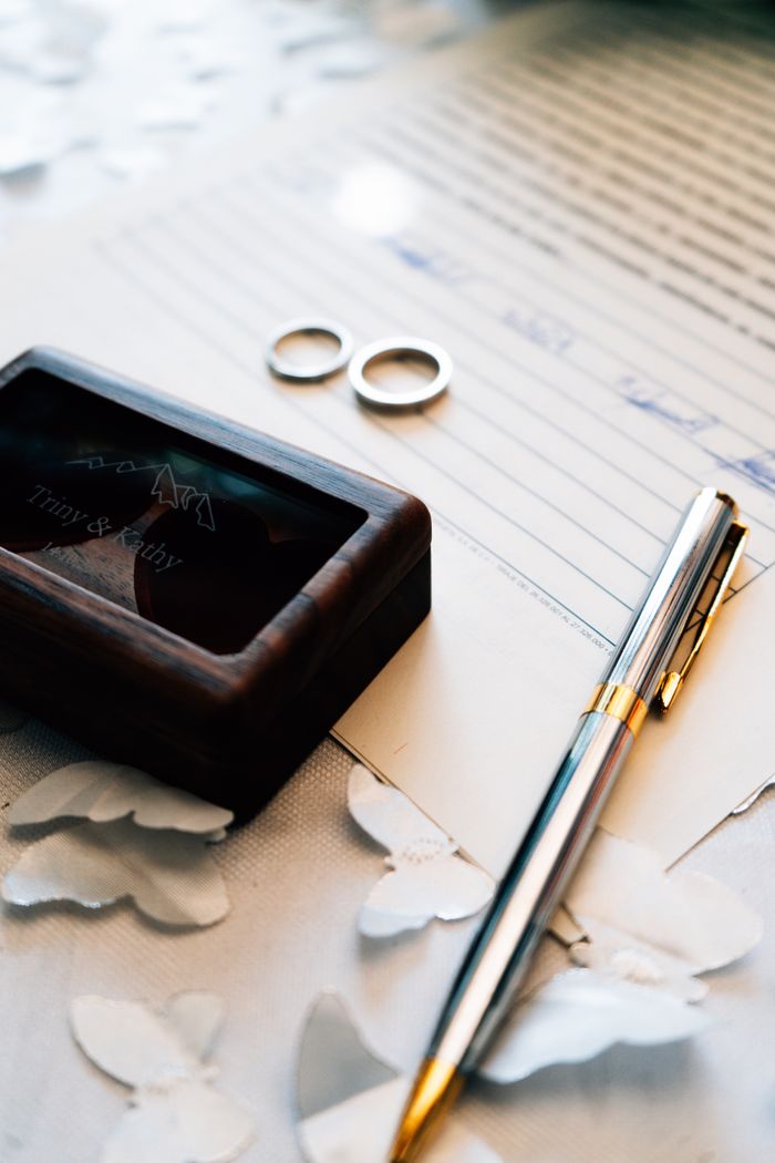 our-story Close-up of wedding rings and pen on a marriage certificate, symbolizing union.